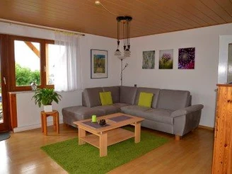 Graues L-förmiges Sofa mit Couchtisch. Blick durch Glastür auf Balkon