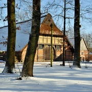 freilichtmuseum-schnee Historische Fachwerkhäuser des Freilichtmuseums Bad Zwischenahn im Schnee, umgeben von Bäumen bei Wintersonne.
