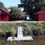 Paddel und Pedal Station  Die Paddel- und Pedalstation zeigt zwei rot gestrichene, skandinavische Holzhütten, umgeben von Natur.