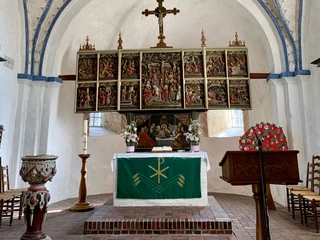 kirche-2 Ein prächtiger Altar mit zahlreichen biblischen Szenen im Inneren einer Kirche, im Zentrum ein Kreuz.