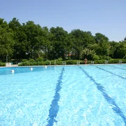 Freibad Ein großes, glitzerndes Freibad mit türkisblauem Wasser, umgeben von üppigem Grün.