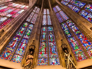 Aachener Dom  Im Aachener Dom befindet sich ein Ensemble aus hoch aufragenden, bunten Glasfenstern. Die lebendigen Farben der Fenster tauchen den Raum in ein mystisches Lichtspiel, ergänzt durch Skulpturen einiger Heiligen darunter.