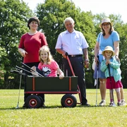 Familie beim Swingolf Eine glückliche Familie, inkl. Kinder und Senioren, genießt Swingolf auf einer grünen Wiese im Sommer.