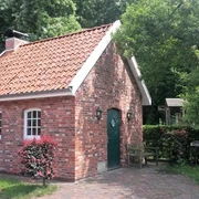 Backhaus an der Hengstforder Mühle Ein Backhaus aus rotem Ziegelstein mit Satteldach, umgeben von grünen Bäumen und roten Sträuchern.