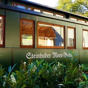 Ein dunkelgrüner Waggon mit großen Fenstern zeigt den Schriftzug „Steinhuder Meer Bahn“.