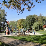 Ein weitläufiger Spielplatz mit modernen Kletteranlagen, umgeben von Bäumen im Park.