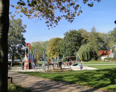 Spielplatz im Park Ein weitläufiger Spielplatz mit modernen Kletteranlagen, umgeben von Bäumen im Park.