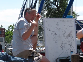 Segelunterricht mit Holger Stintat Holger Stintat zeigt Segelschülern theoretische Grundlagen auf einer Tafel im Freien.