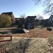Spielplatz am Alten Bahnhof Spielplatz mit Rutsche und Klettergerüst, umgeben von Herbstlaub und ruhigen Wohnhäusern.