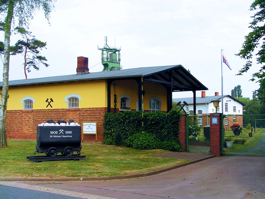 Bergbaumuseum Altenhagen Das Bergbaumuseum Altenhagen zeigt ein gelbes Gebäude mit Förderturm und alten Förderwagen, umgeben von Bäumen.
