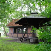 Grillhütte Dudensen Grillhütte Dudensen aus roten Ziegeln mit Walmdach, umgeben von dichtem Laubwald und grünem Rasen.