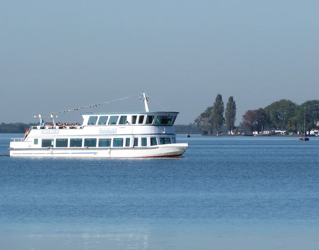 Personenschiff Steinhude Das Bild zeigt ein weißes Passagierschiff namens "Steinhude" auf dem Steinhuder Meer mit blauen Himmel im Hintergrund.