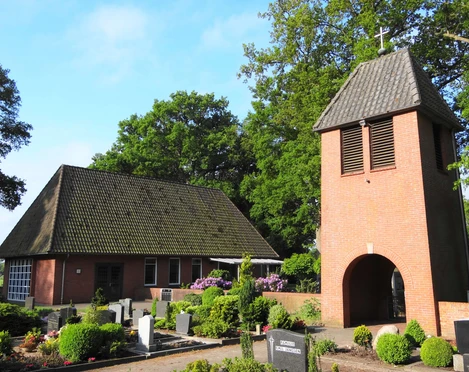 Kapelle Nordloh Kapelle Nordloh: Historische Backsteinkapelle mit markantem Turm, umgeben von gepflegten Gräbern.