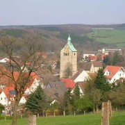 Blick über die Dächer von Neuenbeken auf den steinernen Turm der Pfarrkirche St. Marien.