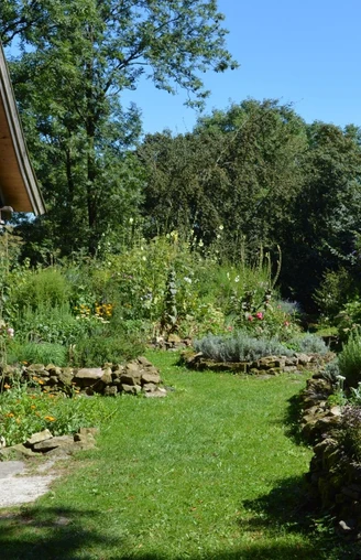 Burg Ravensberg - Bauerngarten Der Bauerngarten an Burg Ravensberg mit üppigen Beeten, Steinwegen und rustikalem Holzschuppen.