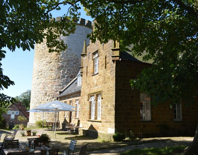 Burg Ravensberg Burg Ravensberg mit massiven Steinturm und restaurierter Fassade, umgeben von grünen Bäumen.