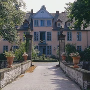 Gutshof Engershausen Historisches Herrenhaus mit gelber Fassade, symmetrischen Fenstern und Natursteinsäulen vor dem Eingang.