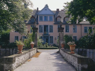 Gutshof Engershausen Historisches Herrenhaus mit gelber Fassade, symmetrischen Fenstern und Natursteinsäulen vor dem Eingang.