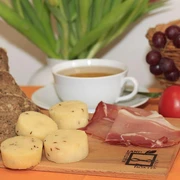 Brot, Käse und Schinken - Leckereien aus Nieheim Brot, Käse mit Kümmel und Schinken auf Holzbrett, begleitet von Kaffeetasse und Trauben.