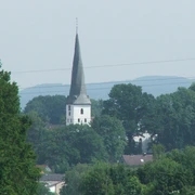 Die Dorfkirche Heiden mit ihrem spitzem Turm ist von üppigem Grün umgeben und durch Bäume eingebettet.