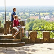 Schöne Aussicht in Hörstel Zwei Wanderer genießen von einer steinernen Plattform aus den weiten Blick über eine grüne Landschaft.
