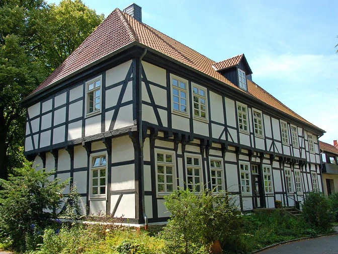 Herrenhaus in Stift Quernheim Das Herrenhaus in Stift Quernheim aus Fachwerk steht inmitten einer grünen Umgebung neben Bäumen.