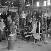Glasmacher mit Arbeitsgerät um 1930 Eine Gruppe von Glasmachern in einer Werkstatt um 1930, ausgestattet mit traditionellen Werkzeugen.
