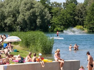 Wasserskianlage Nesthauser See Menschen genießen einen sonnigen Tag am Nesthauser See, während jemand im Wasser Wasserski fährt.