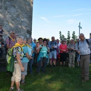 Wandergruppe am Aussichtsturm Eine Wandergruppe steht neben einem steinernen Aussichtsturm und hört einem Guide zu, der in die Ferne zeigt.