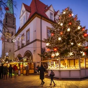 Bielefelder Weihnachtsmarkt Weihnachtsmarkt in der Dämmerung mit festlich beleuchtetem Baum und traditionellen Buden.