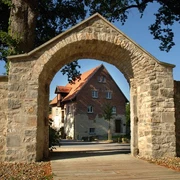 Hörstel - Kloster Gravenhorst Steinbogen mit Blick auf ein historisches Klostergebäude vor blauem Himmel in Hörstel, Gravenhorst.