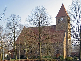 Kirche Kirchlengern Steinernen Kirche Kirchlengern mit rotem Dach, Glockenturm und kahlen Bäumen im Vordergrund.
