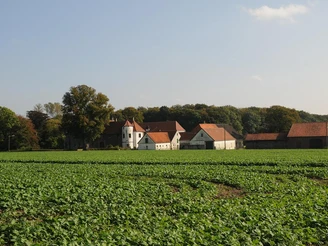 Haus Kilver steht inmitten von weiten Feldern, umgeben von Bäumen und eingebettet in ländlicher Umgebung.