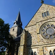 Romanische Kirche St. Bartholomäus mit markantem Glockenturm und beeindruckendem Rundfenster.