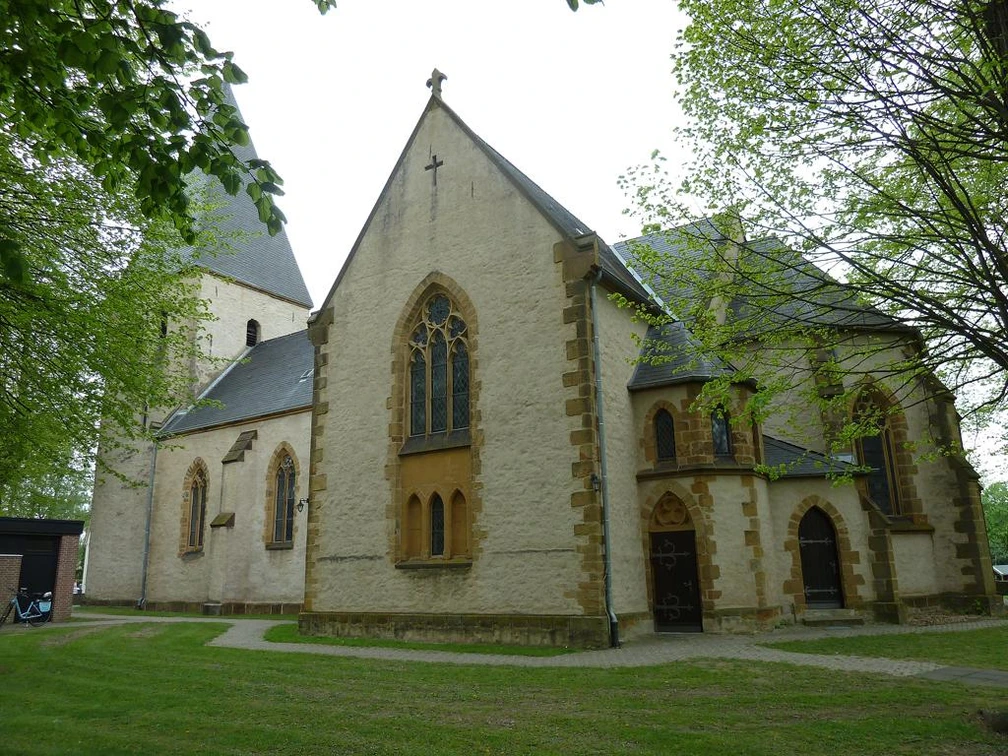 St.-Martins-Kirche mit gotischem Spitzfenster, umgeben von grünem Laub und einem gepflegten Rasen.