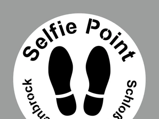 Selfie-Point SHS Schablone Kreisförmiges Schild mit der Aufschrift "Selfie Point Schloss Holte-Stukenbrock", darunter Fußabdrücke.