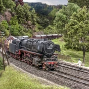 Modellbundesbahn Dampflokomotive Baureihe 44 Dampflokomotive der Baureihe 44 fährt durch eine modellierte Landschaft mit Bäumen und Hügeln.