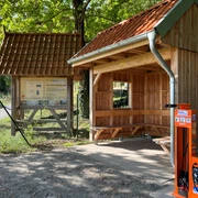 Fahrrad-Reparaturstation Achim Fahrrad-Reparaturstation neben hölzerner Unterstandshütte und Infotafel, umgeben von Bäumen.
