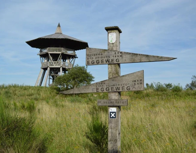 Eggeturm an der Preussischen Velmerstot Eggeturm aus Holz auf einer Wiese; Wegweiser Richtung Eggeweg und Preußische Velmerstot im Vordergrund.