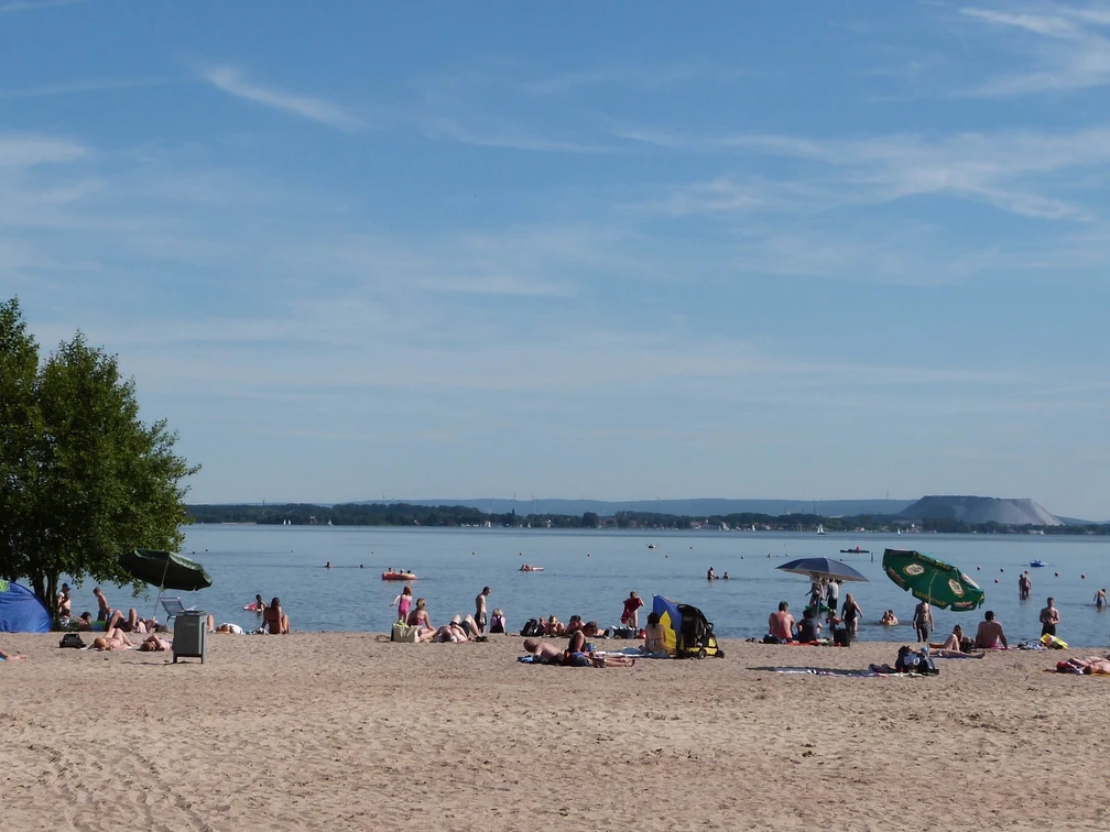Der Badestrand in Mardorf, belebt und sonnig, lädt ein zum Entspannen am klaren, ruhigen Wasser.