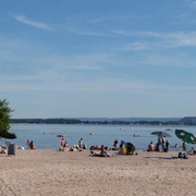 Der Badestrand in Mardorf, belebt und sonnig, lädt ein zum Entspannen am klaren, ruhigen Wasser.
