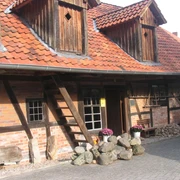 Kastenmangel in Steinhude Historisches Fachwerkhaus mit rotem Ziegeldach, Holzverzierung und farbenfrohen Pflanzen im Vorgarten.