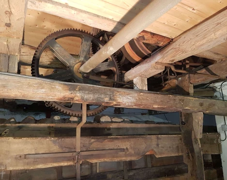 Kastenmangel Antrieb Alte Holzwassermühle mit rustikalen Zahnrädern und Balken, die historische Ingenieurskunst zeigt.