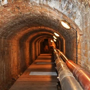 Unterirdischer Solegang in Bad Rothenfelde Zout water stroomt door de ondergrondse gang van de bron naar de gradeerwerken in Bad RothenfeldeBackstein-Gewölbetunnel mit Röhren und schwacher Beleuchtung entlang des Weges.