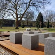 De Bijbeltuin in Bad Rothenfelde De Bijbeltuin in Bad Rothenfelde bij het Nieuwe GradeerwerkGranitblöcke auf rostfarbenem Untergrund in einem Park mit Bäumen im Hintergrund.