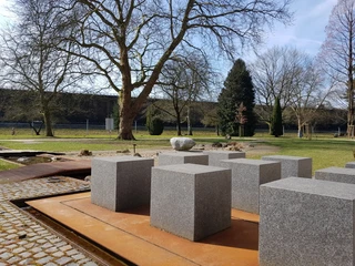 De Bijbeltuin in Bad Rothenfelde De Bijbeltuin in Bad Rothenfelde bij het Nieuwe GradeerwerkGranitblöcke auf rostfarbenem Untergrund in einem Park mit Bäumen im Hintergrund.