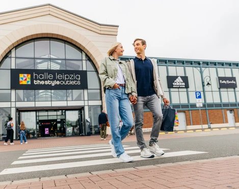 Halle Leipzig The Style Outlets - Shopping in Leipzig Ein Paar verlässt lachend und mit Einkaufstüten in der Hand das Halle Leipzig The Style Outlets Center, Shopping, Einkaufen, Freizeit, Familie, Ausflug