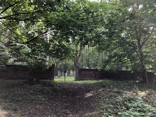 Jüdischer Friedhof  Eingebettet in dichte Bäume, liegt der historische jüdische Friedhof mit seinem geschlossenen Gittertor.