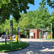 Parkplatz Bruchdamm Kassenautomat Kassenautomat am Parkplatz Bruchdamm, umgeben von Bäumen und parkenden Autos bei sonnigem Wetter.