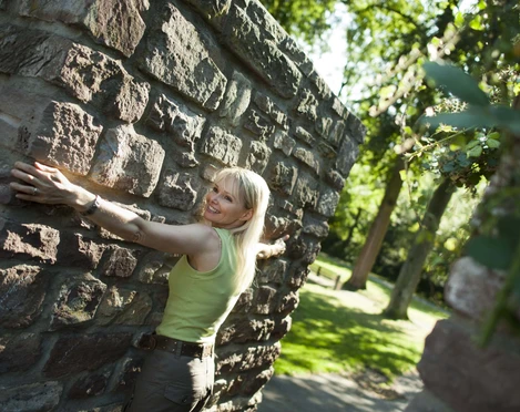 hx-stadtentdecken-andreashub-4 Frau an einem Durchgang der historischen Stadtmauer mit ausgebreiteten Armen, um zu zeigen wie dich die Mauer ist